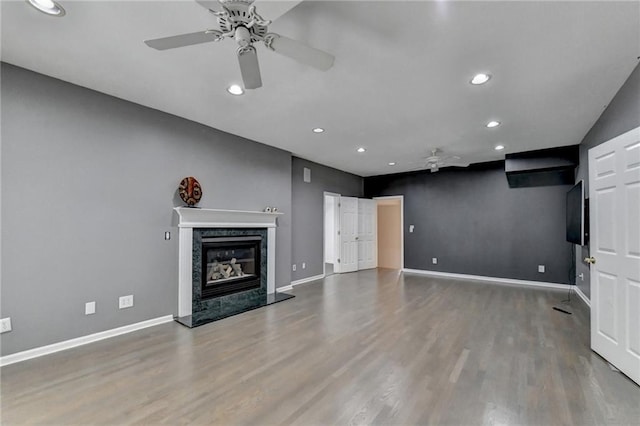 unfurnished living room featuring ceiling fan, recessed lighting, a fireplace, wood finished floors, and baseboards