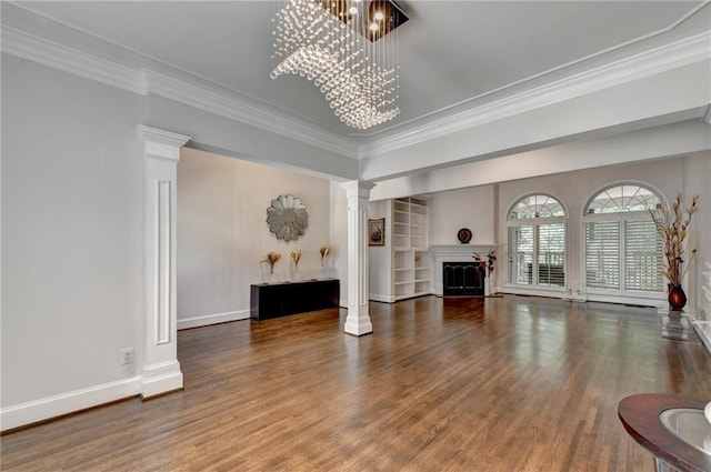 living room with a fireplace, wood finished floors, decorative columns, and an inviting chandelier