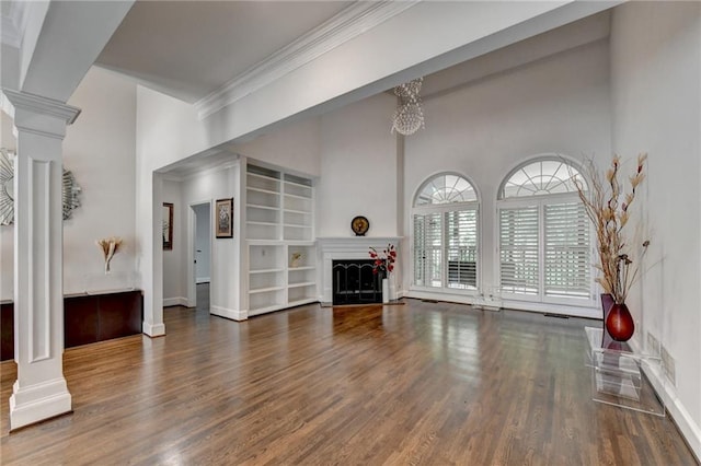 living room with a fireplace, decorative columns, a high ceiling, ornamental molding, and wood finished floors