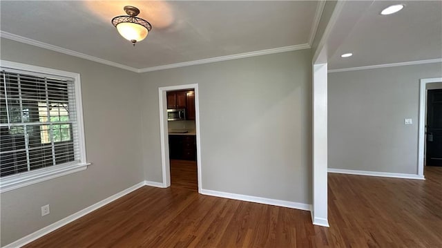spare room featuring wood finished floors, ornamental molding, and baseboards