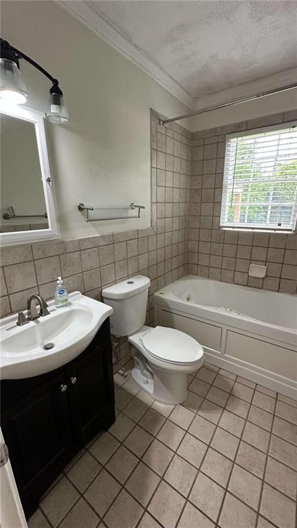 bathroom featuring tile walls, vanity, toilet, ornamental molding, and tile patterned flooring