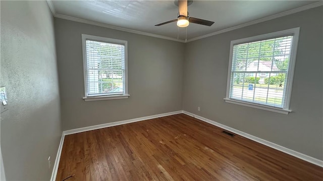 spare room featuring dark wood-style flooring, a healthy amount of sunlight, crown molding, and baseboards