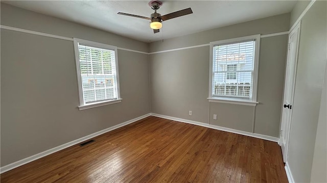 empty room featuring dark wood finished floors, visible vents, ceiling fan, and baseboards