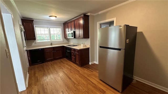 kitchen with crown molding, light countertops, baseboards, black appliances, and wood finished floors
