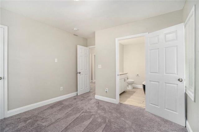 unfurnished bedroom with ensuite bathroom and light colored carpet