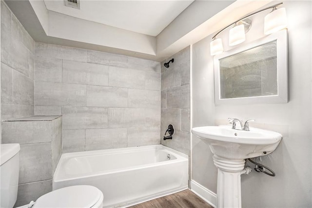 full bathroom featuring hardwood / wood-style floors, sink, toilet, and tiled shower / bath