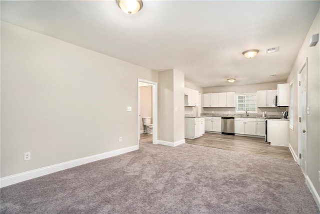 unfurnished living room with sink and light colored carpet