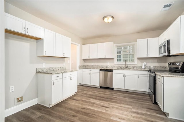 kitchen with wood-type flooring, white cabinetry, and stainless steel appliances