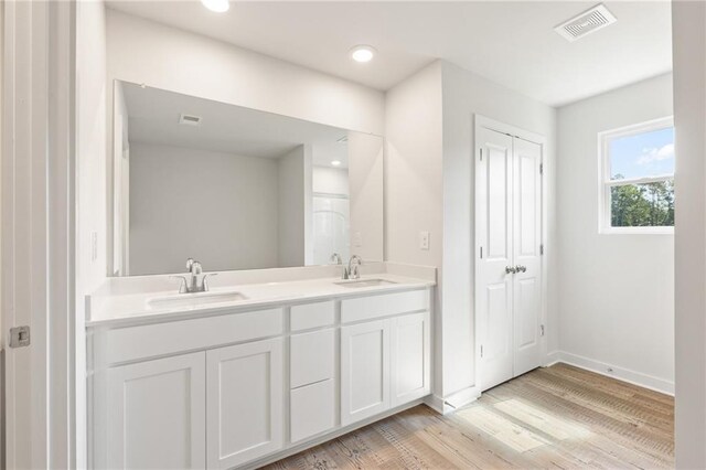bathroom with double vanity, wood finished floors, a sink, and visible vents