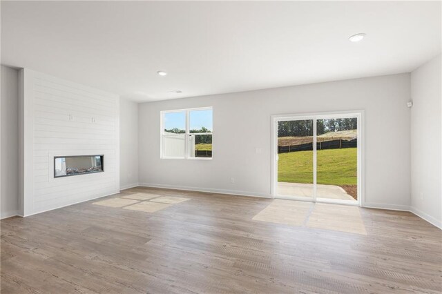 unfurnished living room featuring recessed lighting, a fireplace, wood finished floors, and baseboards