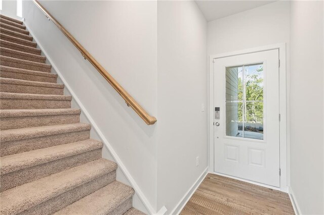 entryway featuring stairs, light wood-style flooring, and baseboards