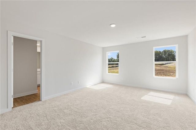 carpeted empty room with visible vents and baseboards