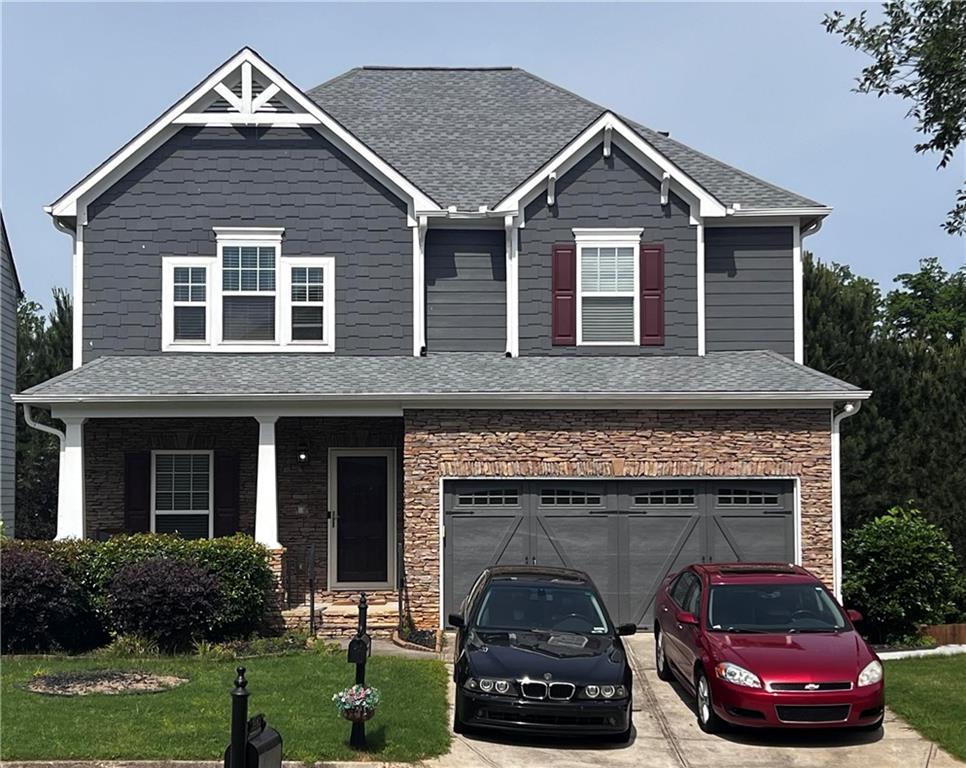 3864 Lake Sanctuary Way, Atlanta, GA 30349 - craftsman-style home featuring concrete driveway, an attached garage, roof with shingles, stone siding, and a front lawn