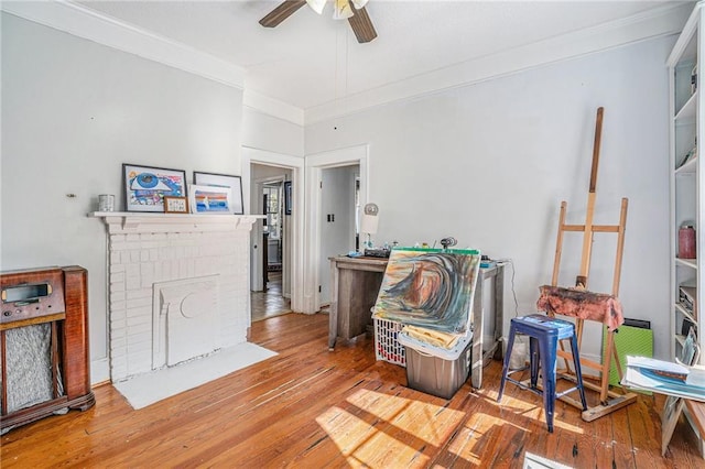 interior space featuring hardwood / wood-style flooring, ceiling fan, a fireplace, and ornamental molding