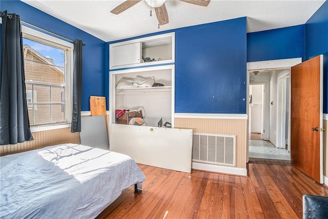 bedroom with a wainscoted wall, a closet, wood finished floors, and visible vents