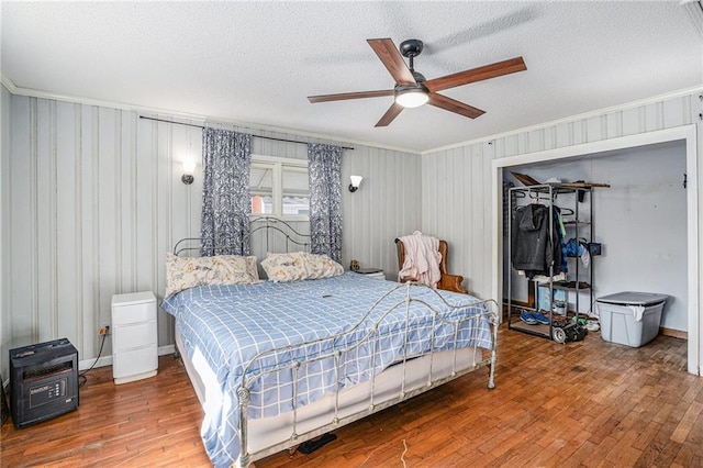 bedroom featuring a textured ceiling, ornamental molding, and wood-type flooring