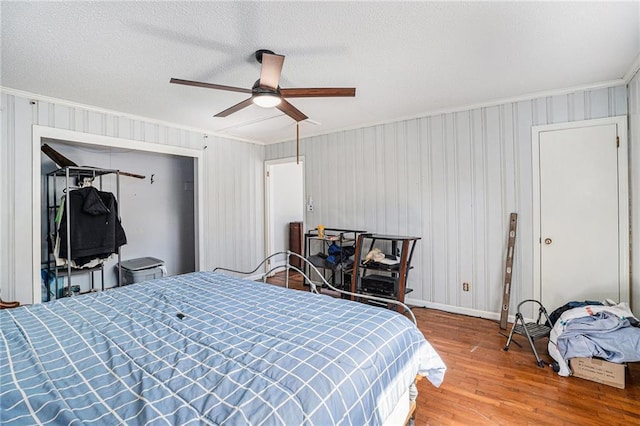 bedroom with ceiling fan, wood finished floors, and crown molding