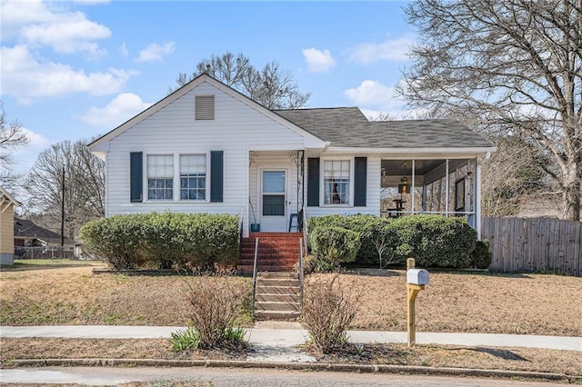 bungalow with a shingled roof and fence