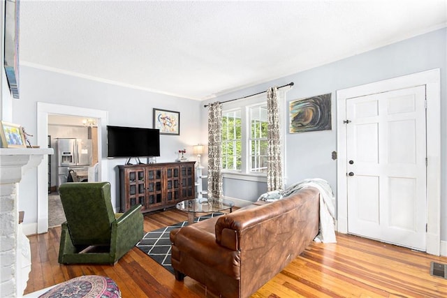 living area with a brick fireplace, wood finished floors, and crown molding
