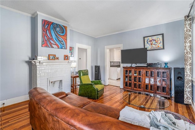 living room with ornamental molding, a brick fireplace, wood finished floors, and baseboards