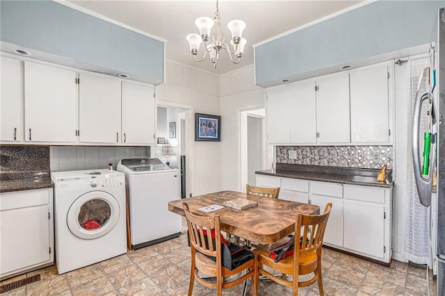 interior space with a notable chandelier, white cabinetry, ornamental molding, independent washer and dryer, and decorative backsplash