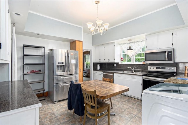 kitchen with stainless steel appliances, ornamental molding, a sink, and washer / clothes dryer