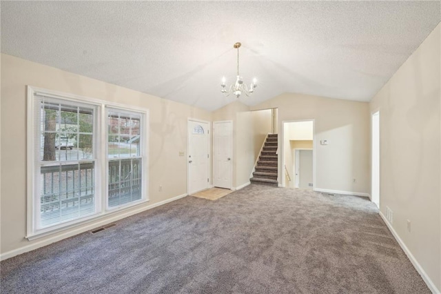 unfurnished room with carpet, a textured ceiling, lofted ceiling, and a notable chandelier