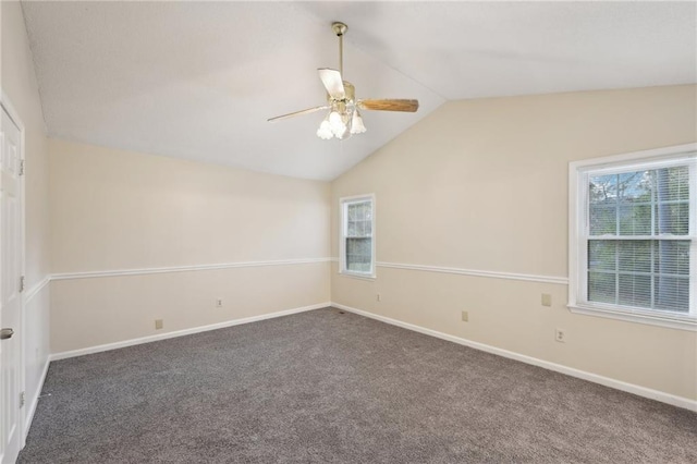 empty room with ceiling fan, dark carpet, and vaulted ceiling