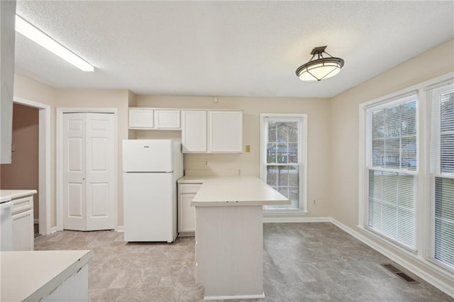 kitchen with white cabinetry, white fridge, and a textured ceiling