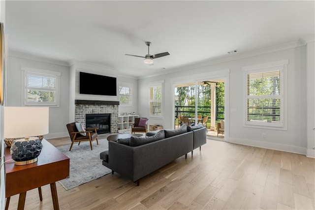 living room featuring a fireplace, ceiling fan, light wood-type flooring, and crown molding