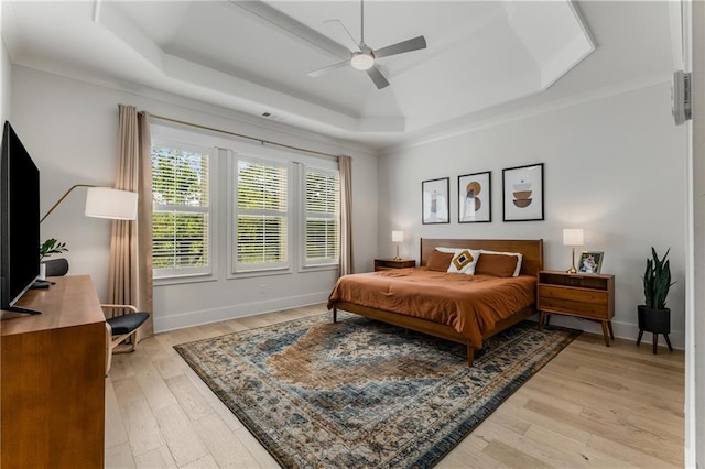 bedroom featuring ceiling fan, a raised ceiling, and light hardwood / wood-style floors