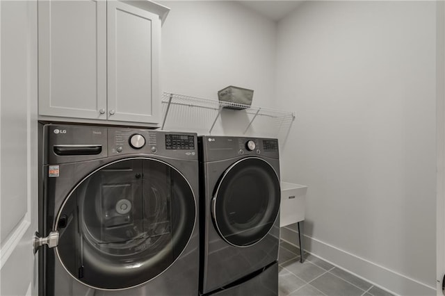 laundry area featuring light tile patterned flooring, washing machine and dryer, and cabinets