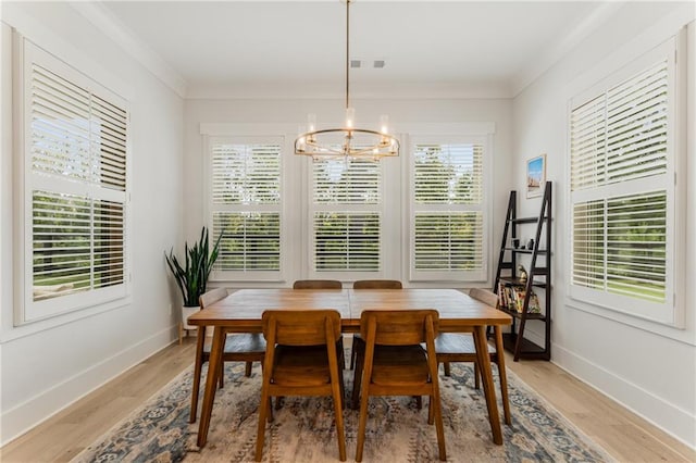 dining room with crown molding, light wood-type flooring, a chandelier, and a wealth of natural light