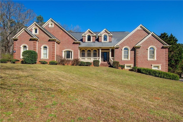 view of front of house featuring a front yard, a porch, and brick siding