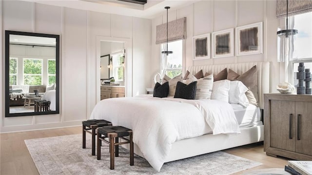 bedroom featuring connected bathroom and light hardwood / wood-style floors