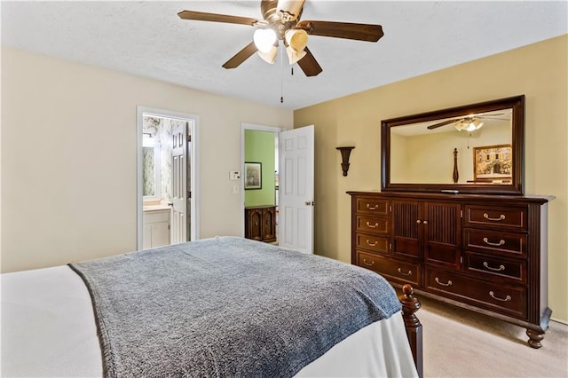 bedroom featuring light colored carpet, a ceiling fan, and connected bathroom
