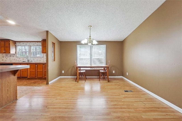 dining room with light wood-type flooring, visible vents, baseboards, and an inviting chandelier