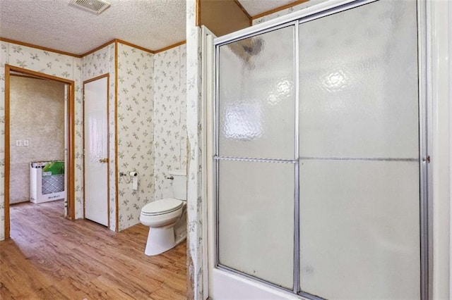 full bathroom with wood finished floors, visible vents, wallpapered walls, an enclosed shower, and a textured ceiling