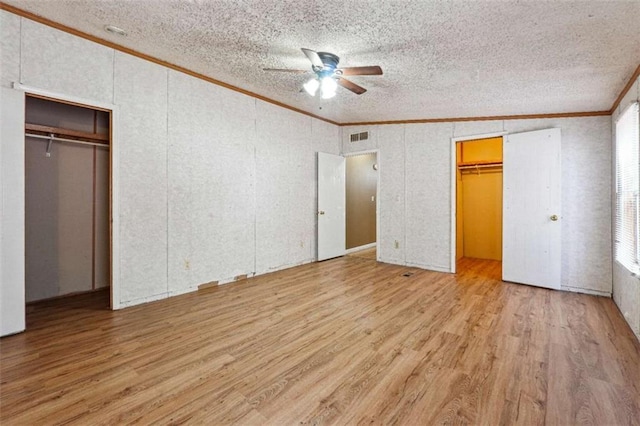 unfurnished bedroom featuring visible vents, light wood-style flooring, ceiling fan, a textured ceiling, and crown molding