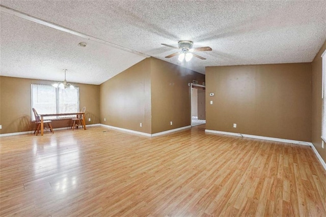 interior space with ceiling fan with notable chandelier, a textured ceiling, light wood-type flooring, and baseboards