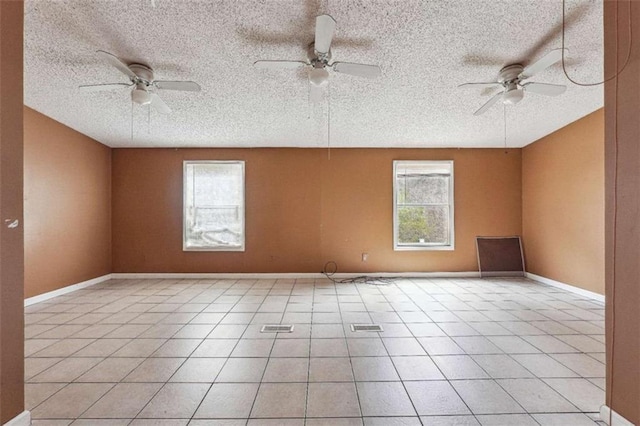 empty room featuring light tile patterned floors, plenty of natural light, baseboards, and ceiling fan