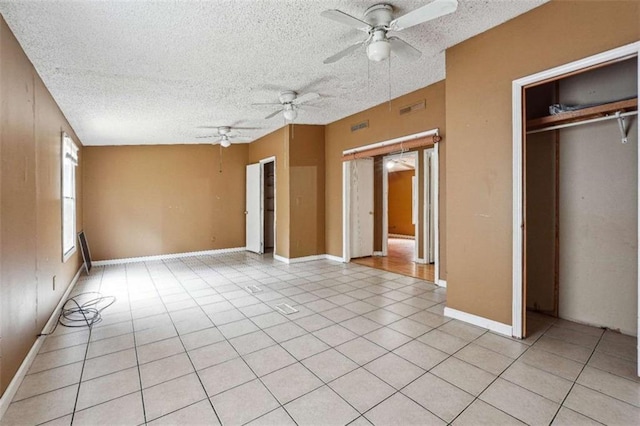 unfurnished bedroom with light tile patterned flooring, visible vents, a textured ceiling, and a closet