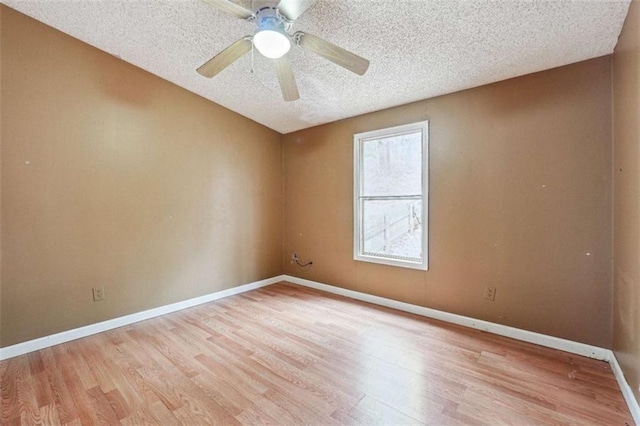 spare room featuring ceiling fan, light wood-style floors, baseboards, and a textured ceiling