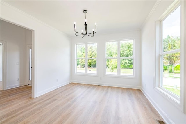 empty room featuring light hardwood / wood-style floors, a wealth of natural light, and a chandelier