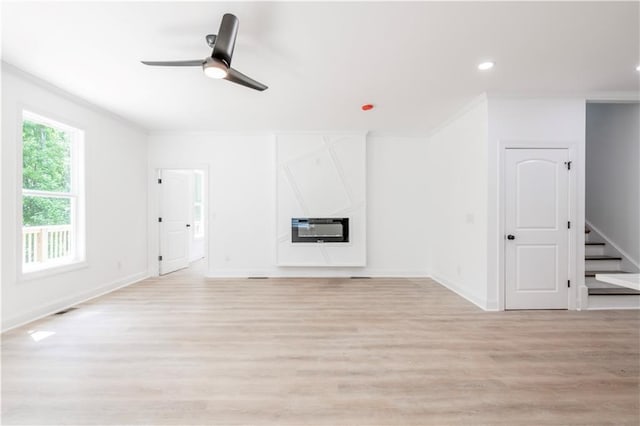 unfurnished living room with ceiling fan, heating unit, crown molding, and light hardwood / wood-style flooring