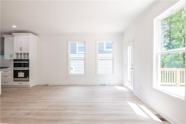 unfurnished living room featuring light wood-type flooring and ornamental molding