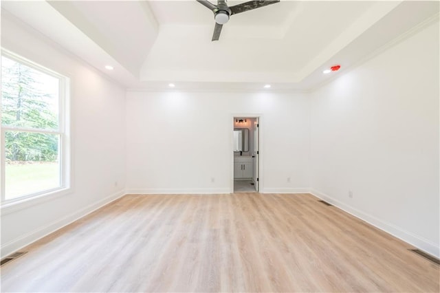 spare room featuring ceiling fan, a tray ceiling, and light hardwood / wood-style floors