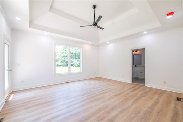 empty room featuring ornamental molding, a raised ceiling, ceiling fan, and light hardwood / wood-style flooring