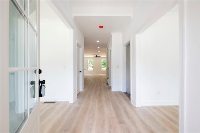 hallway with ornamental molding and light hardwood / wood-style floors