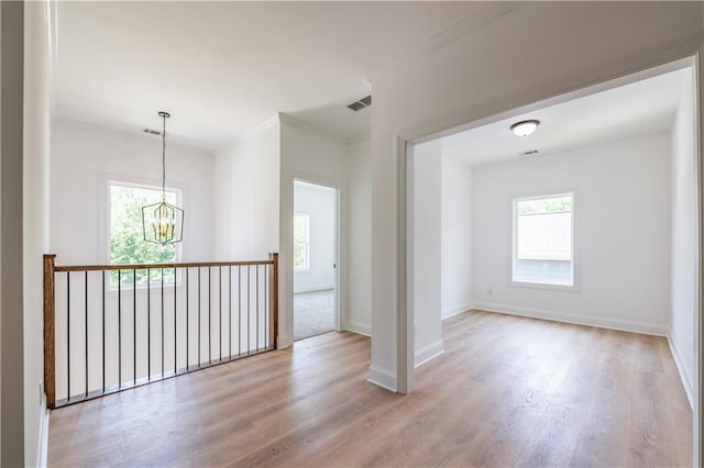 empty room featuring ornamental molding, light hardwood / wood-style floors, and a notable chandelier